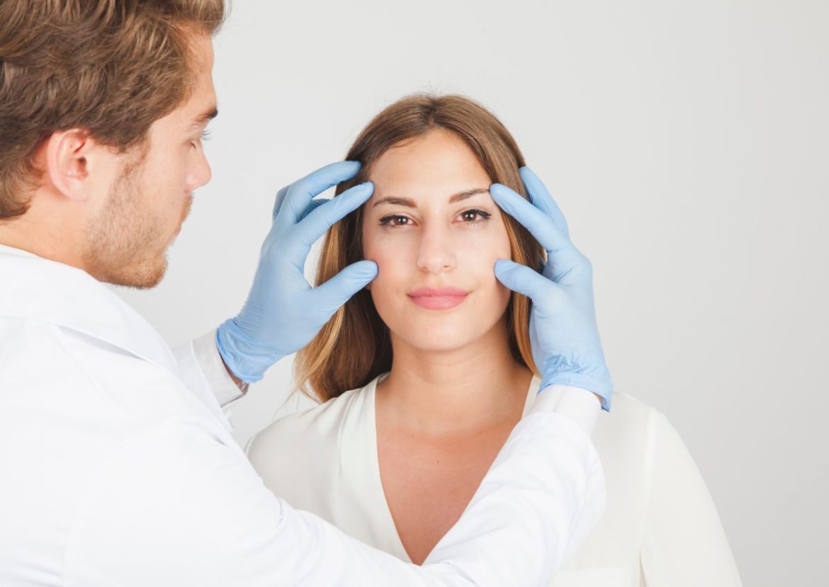 Un chirurgien examine le visage d'une patiente, évoquant une consultation pour la chirurgie esthétique.